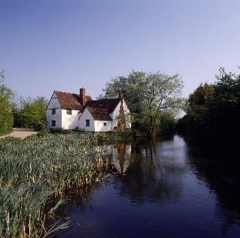 A white rural house adjacent to a country lane and a river